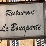 Une pancarte indiquant restaurant le bonaparte accrochée à un immeuble, incarnant la douceur de vivre de Cassis.