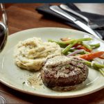 Un steak et une purée de pommes de terre dans une assiette avec un verre de vin, mettant en valeur les jalons de la perfection culinaire.