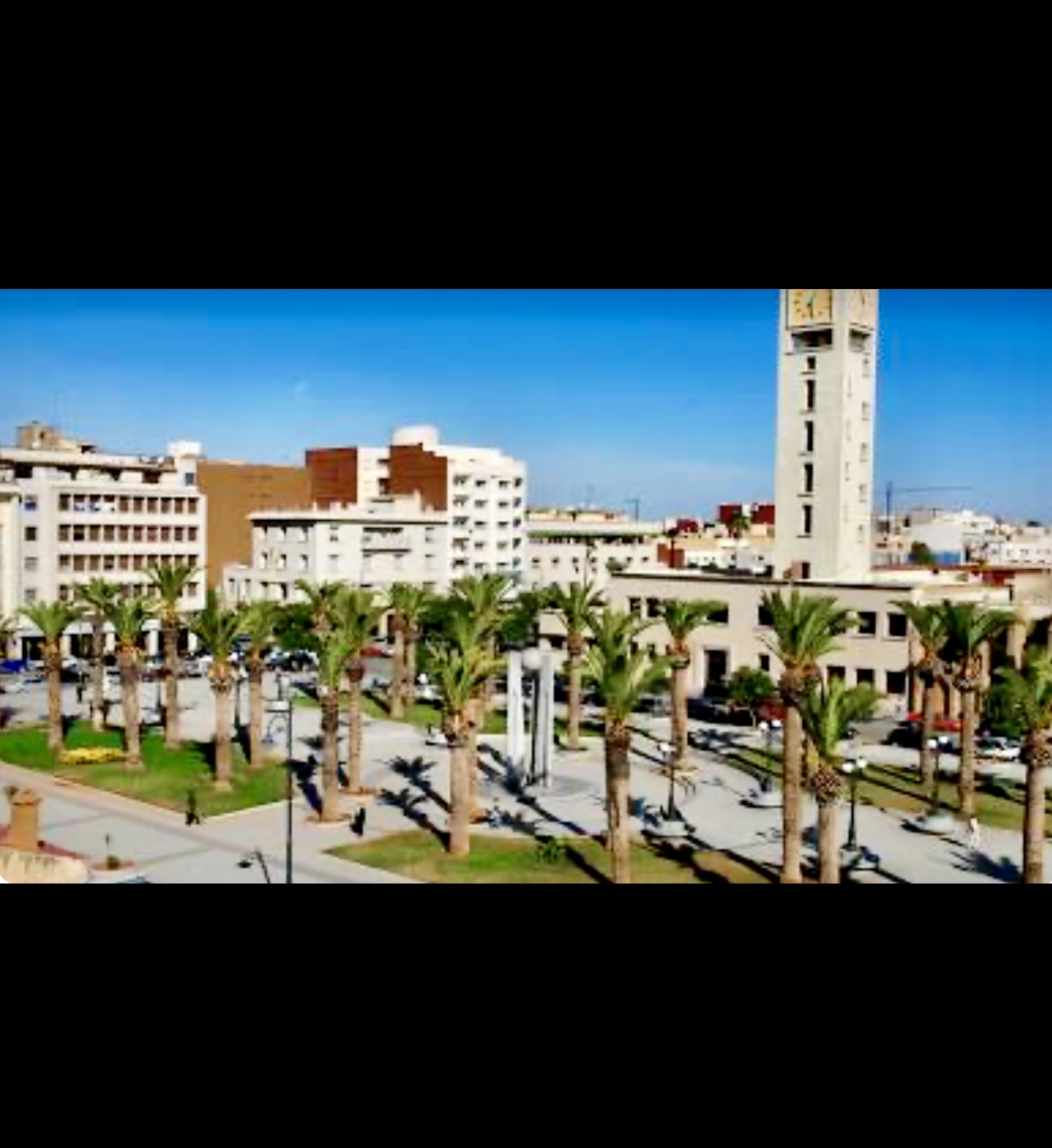 Une ville avec des palmiers et une tour de l'horloge au Maroc/Oujda.