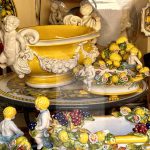 Une exposition de céramiques jaunes et blanches dans une vitrine, mettant en vedette le tout pour votre voyage de Lucca.