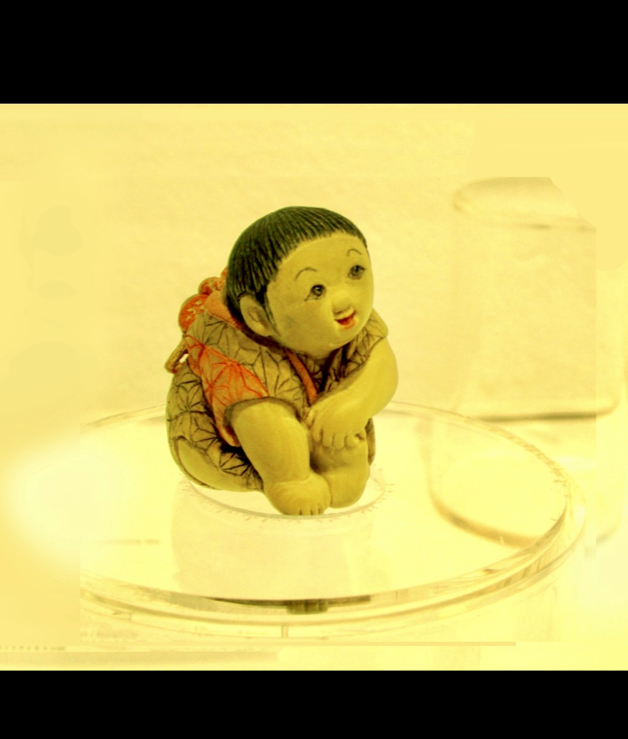 Une figurine miniature Netsuke représentant un bébé assis sur un verre.