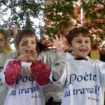 Un groupe d'enfants en t-shirt blanc démontrant leur enthousiasme lors d'un événement Poésie à Trois-Rivières les mains en l'air.