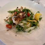 Une salade de poulpe gastronomique élégamment présentée sur une assiette blanche.