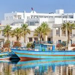 Un groupe de bateaux amarrés à l'eau près d'un bâtiment de La Tunisie au Salon tourisme et voyage.
