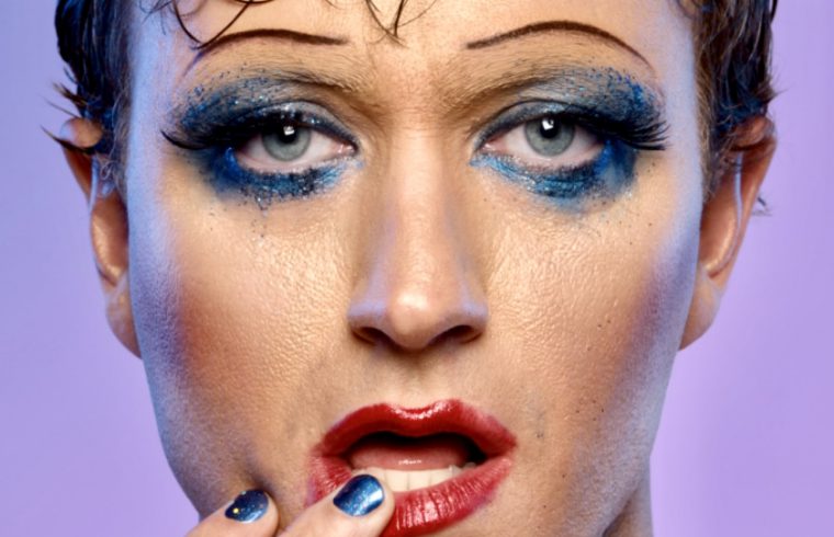 Un homme au maquillage bleu et aux ongles bleus, inspiré d'Hedwige et le pouce en furie.