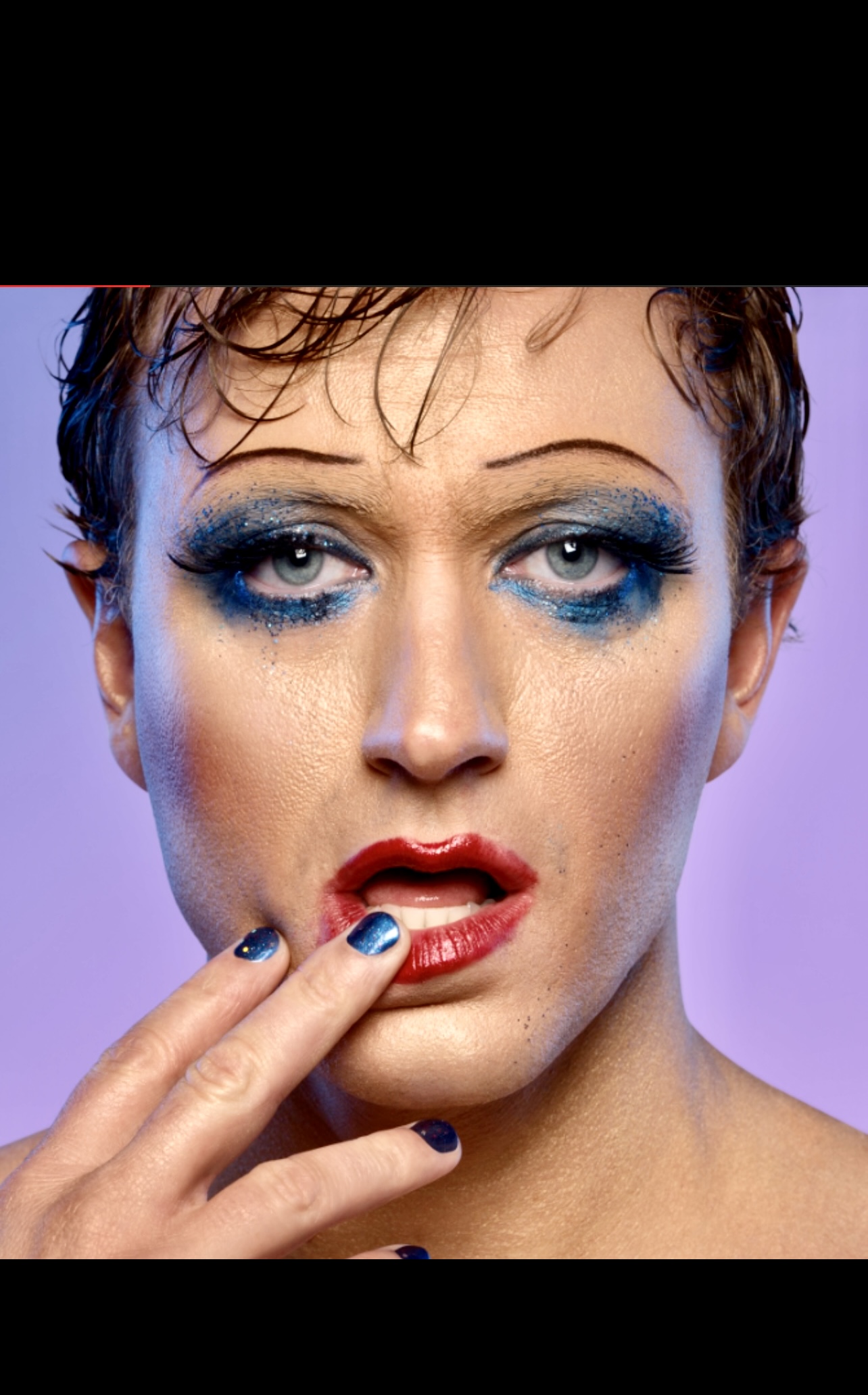 Un homme au maquillage bleu et aux ongles bleus, inspiré d'Hedwige et le pouce en furie.