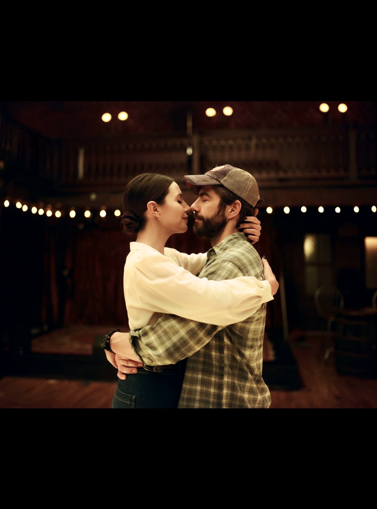 Un homme et une femme s’embrassant dans une pièce faiblement éclairée.