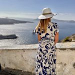 Une femme vêtue d'une robe bleue et blanche profitant de la magnifique vue sur l'océan en Grèce.
