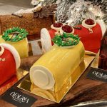 Faure présente une divine exposition de gâteaux de Noël devant un sapin de Noël joliment décoré.