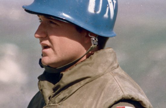 Un homme portant un casque sur lequel figure un drapeau canadien, symbolisant la fierté nationale et la coopération internationale, dans un contexte de guerre et de droit international.