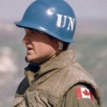 Un homme portant un casque sur lequel figure un drapeau canadien, représentant le lien entre la guerre et le droit international.
