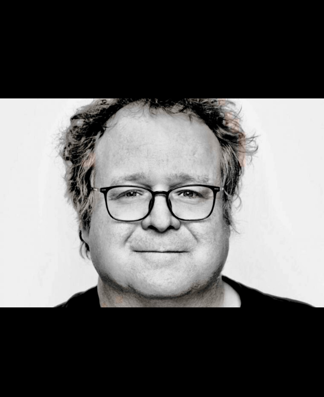 Une photo en noir et blanc d'un homme à lunettes, dressant le portrait de Jean-Sébastien Huot de manière captivante et narrative.