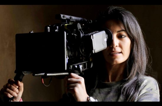 Le cinéma intimiste de Maryam Touzani capture une femme tenant une caméra sur un fond sombre.