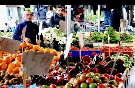 Un homme se tient dans un marché animé rempli de fruits et de légumes pendant la semaine de la cuisine italienne.