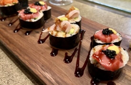 Sushi sur une planche de bois dans un restaurant avec de la sauce dessus.