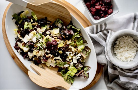 Une salade avec des canneberges et du riz sur une planche en bois.