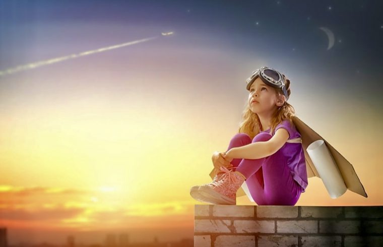 Une petite fille assise sur un mur de briques au coucher du soleil, entourée d'une aura de spiritualité.