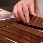 Joane L'Heureux découpe habilement des barres de chocolat décadentes sur un plateau.