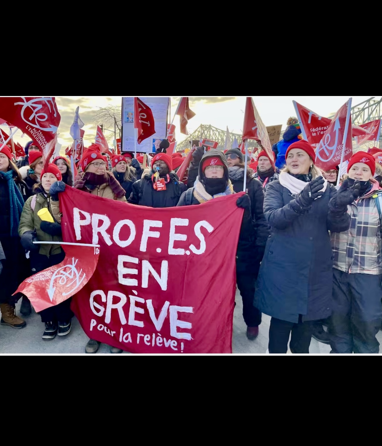 Un groupe d’enseignants brandissant des pancartes indiquant profes en greve.