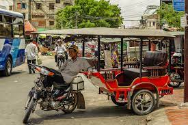 Un homme se déplaçant en rickshaw dans une rue animée.
